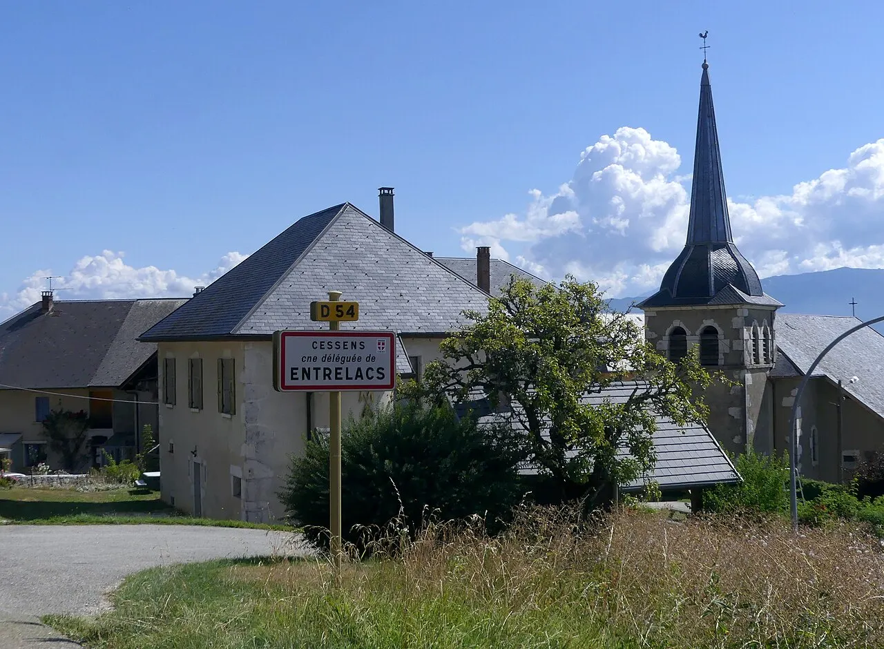 Vue du panneau d'entrée dans le village de Cessens (commune déléguée d'Entrelacs), dont l'église est visible à droite, en Savoie.
