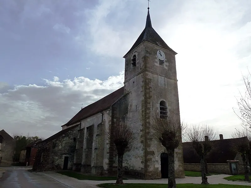 Grande église en pierres précédée d'une tour porche à 3 niveaux surmontée d'un clocher pavillon terminé par une flèche en ardoise