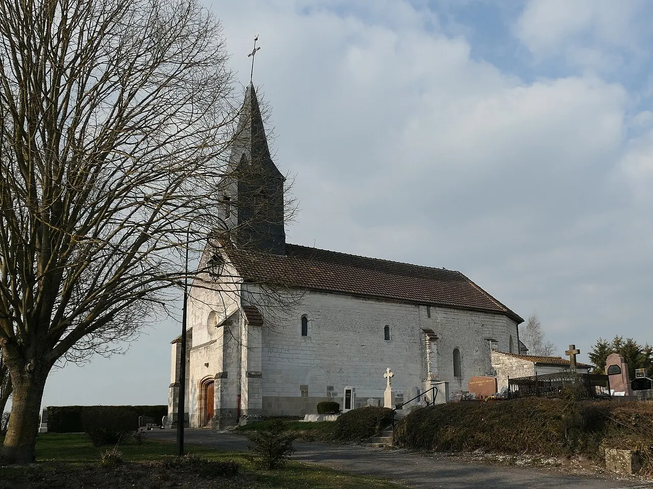 Eglise en craie blanche, couverte en ardoise, clocher pavillon, entourée du cimetière