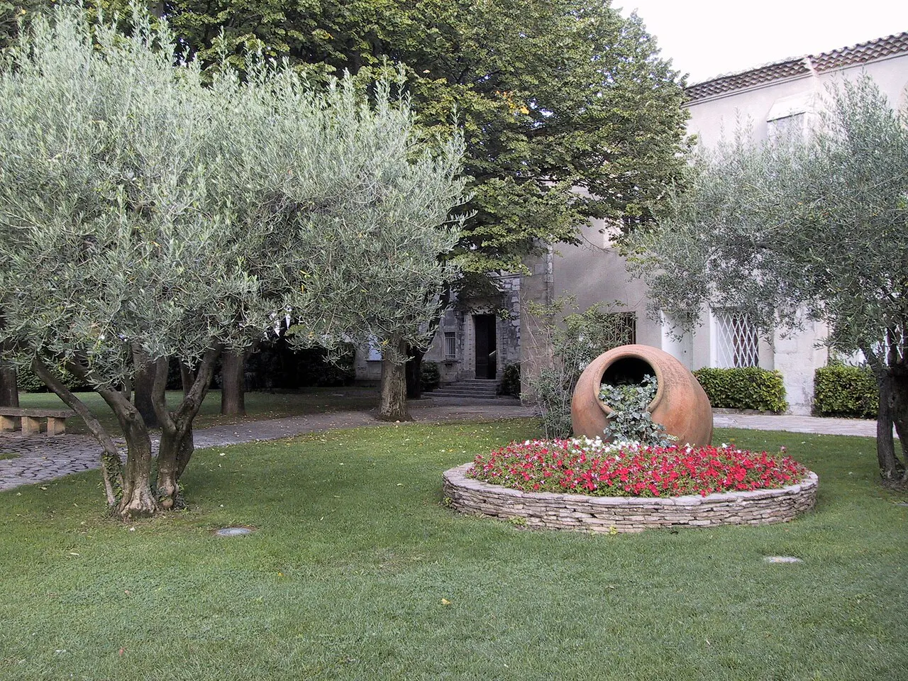Le jardin de la mairie de Garons, France. L'image présente une pelouse arborée avec un parterre de fleurs. A l'arrière on distingue le…
