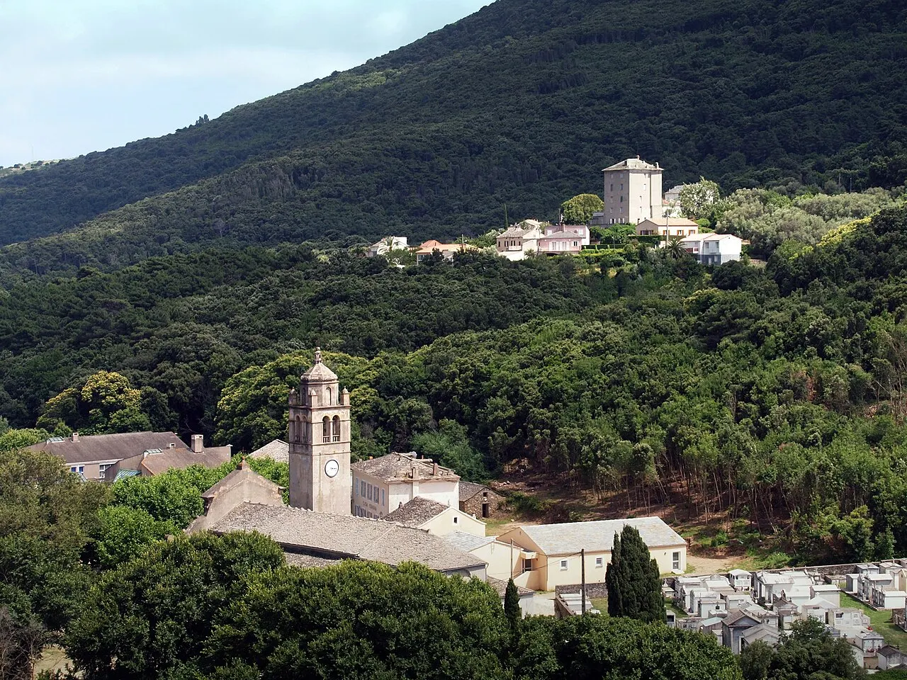 Luri (Corse) - Piazza dont on voit le clocher de l'église SS. Pietro e Paolo et le cimetière. Au fond, Castiglione