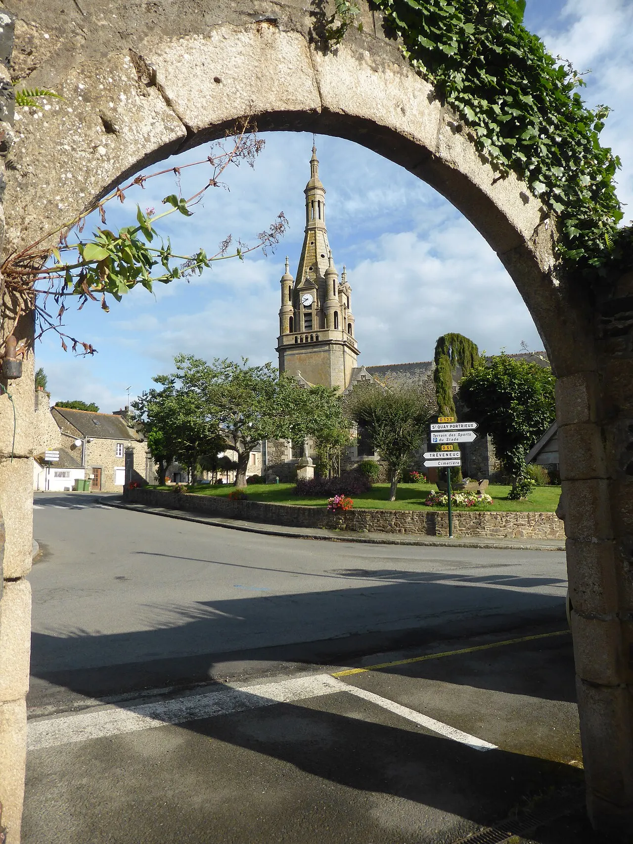 L'église Saint-Pierre de Plourhan, dans les Côtes-d'Armor, vue à travers une arche près de la mairie.