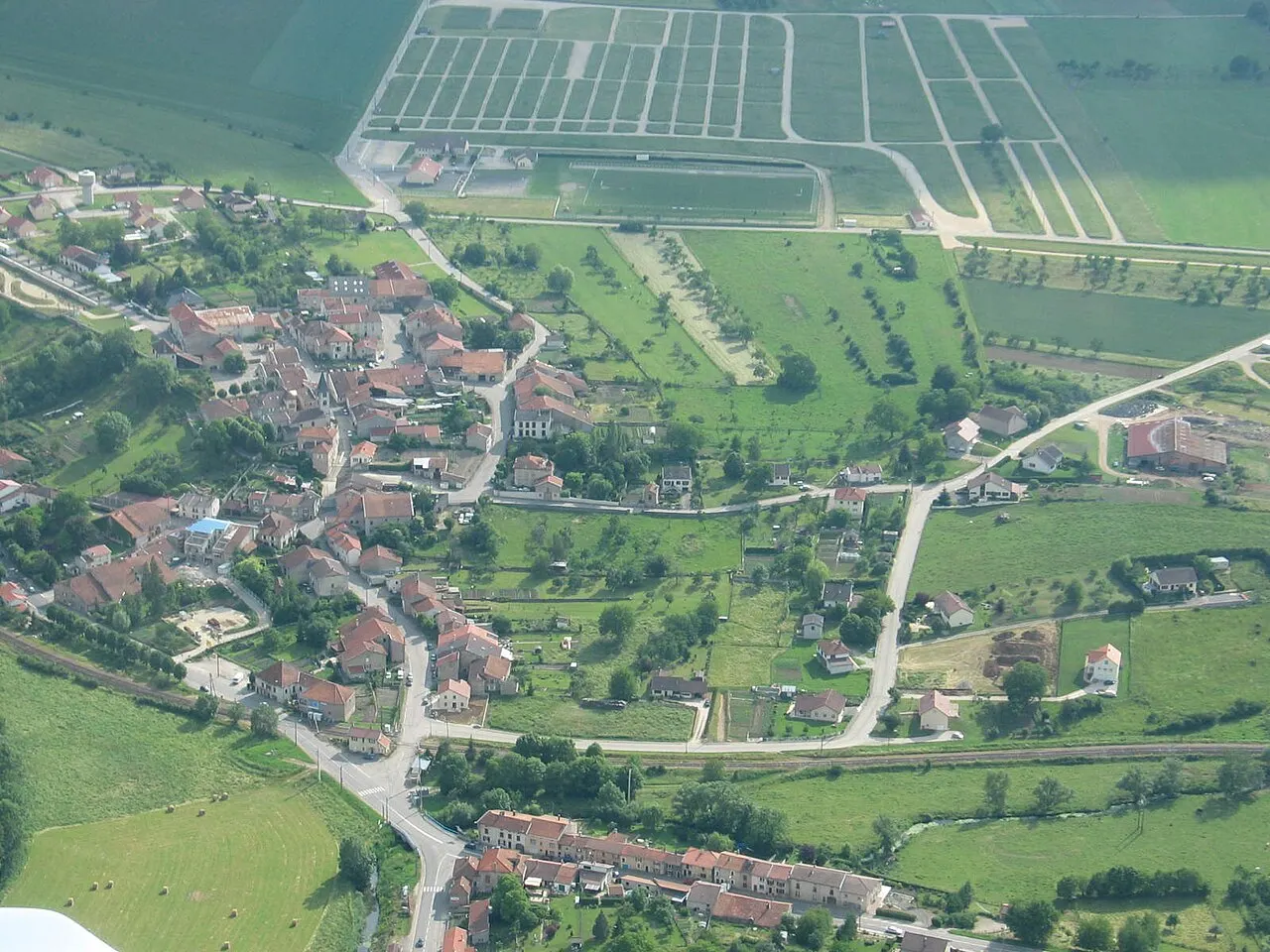 Vue aérienne sur la partie bourg de Poussay avec le champ de foire en arrière plan.