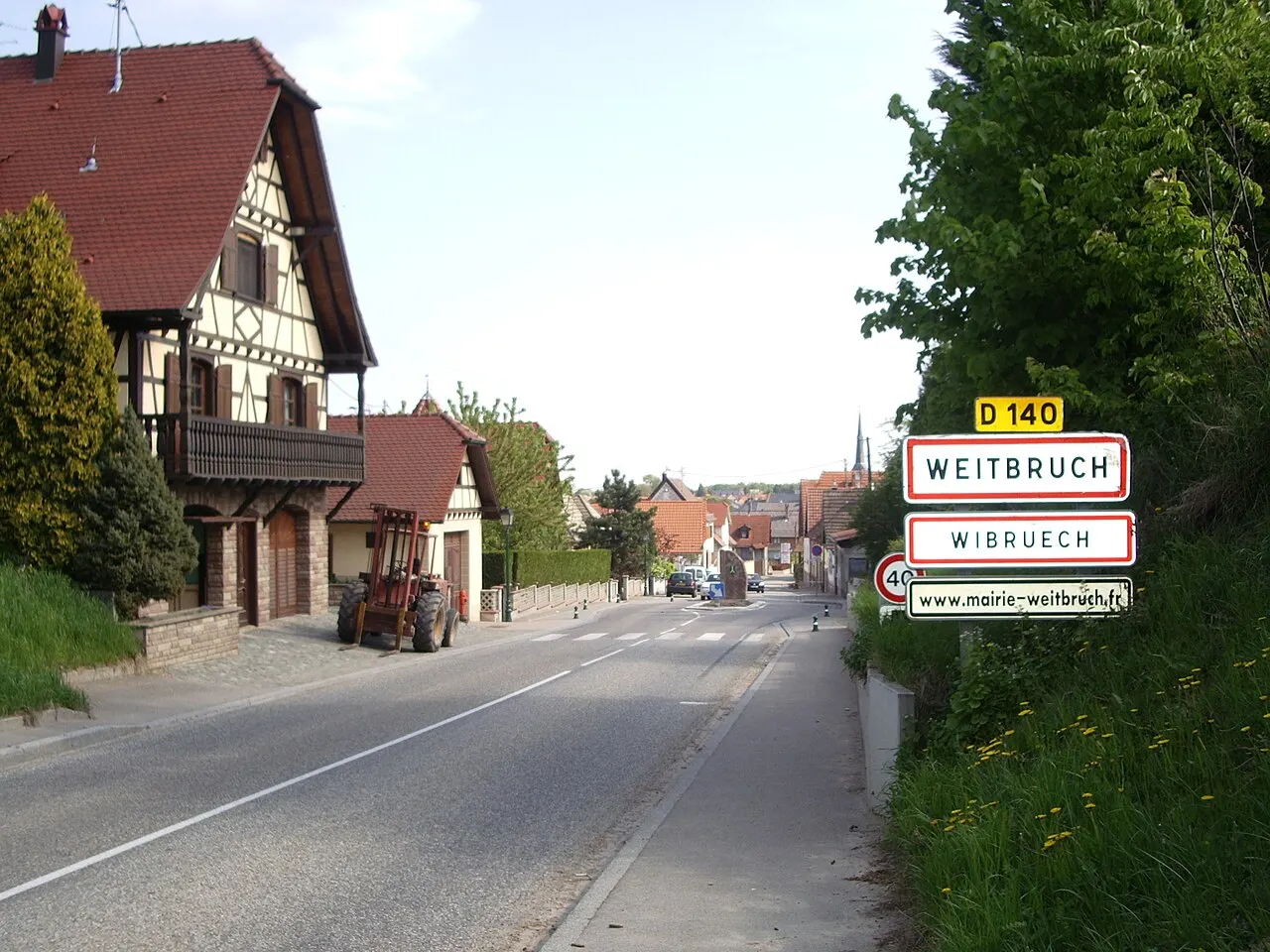 Vue de l'entrée Sud de Weitbruch, rue de Brumath. La photo montre également le panneau de la commune avec sa version alsacienne et…